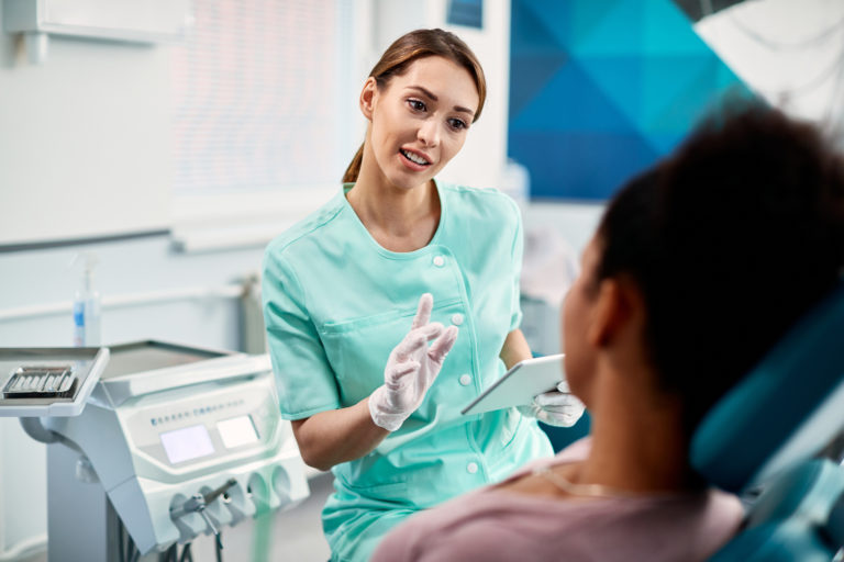 翻瓣手術大解析,醫師淺談翻瓣手術及後遺症 3 Young Female Dentist Communicating With Patient Before Dental Procedure At Dentist S Office